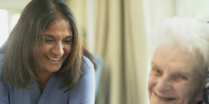 Smiling nurse with an elderly patient in a room, reflecting the warmth of care work