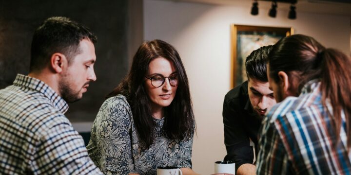 Four people reviewing documents together at a wooden table in a workspace