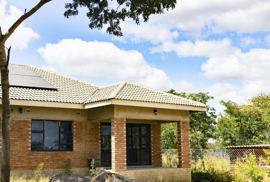 Brick house with a veranda and solar panels on its tiled roof under a blue sky
